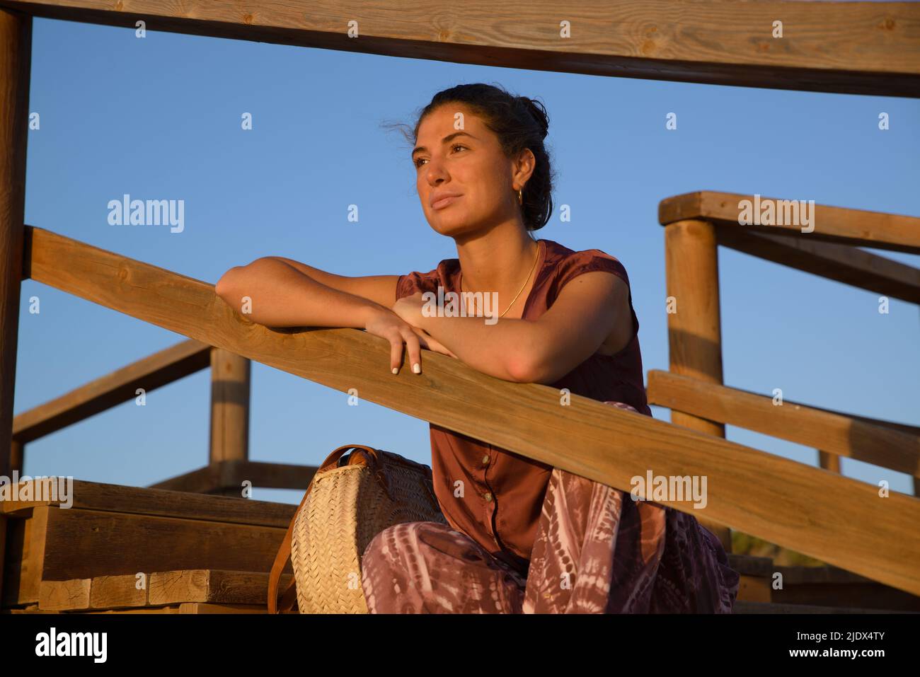Caucasian young woman happy and sitting on the sand on the beach enjoy sunrise Stock Photo