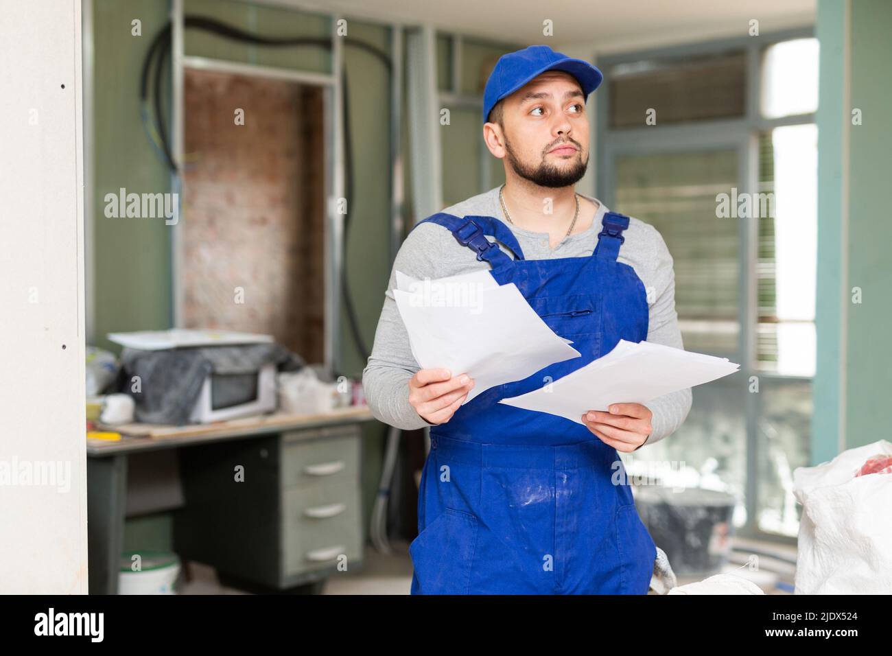 Foreman reading papers on indoor construction site Stock Photo