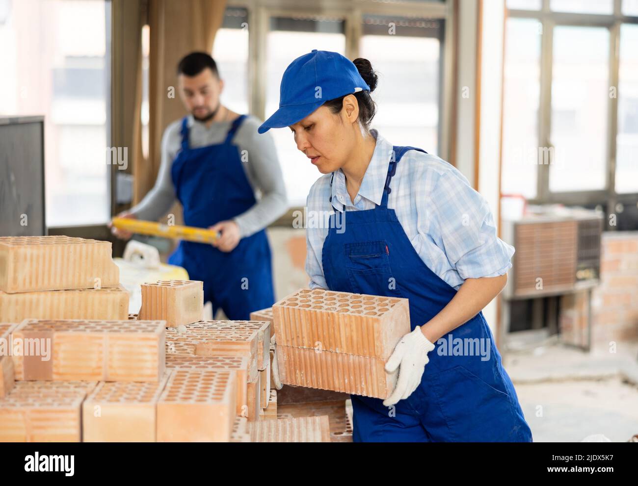 Female builder stacking red bricks at construction site indoors Stock ...