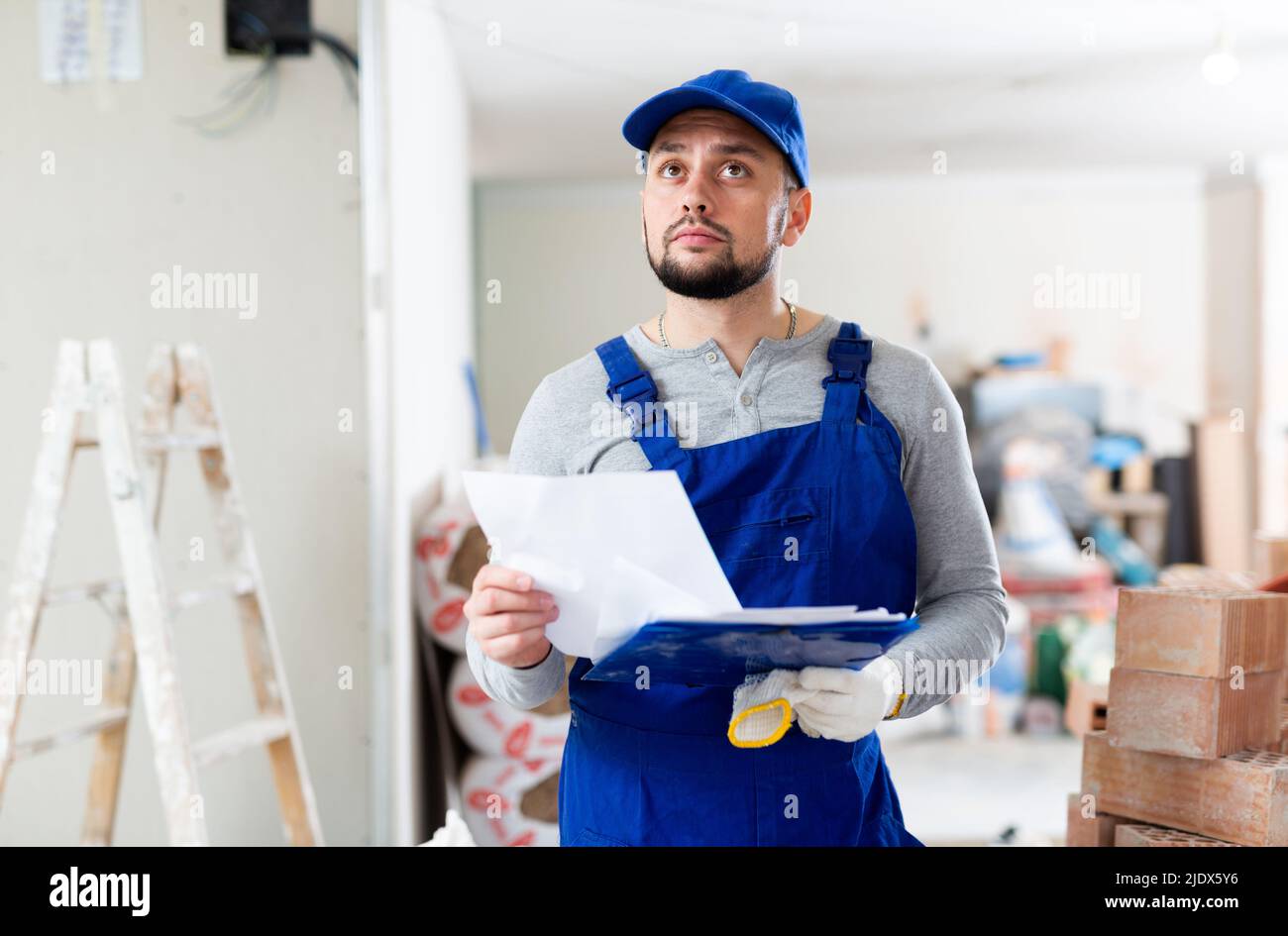 Foreman reading papers on indoor construction site Stock Photo