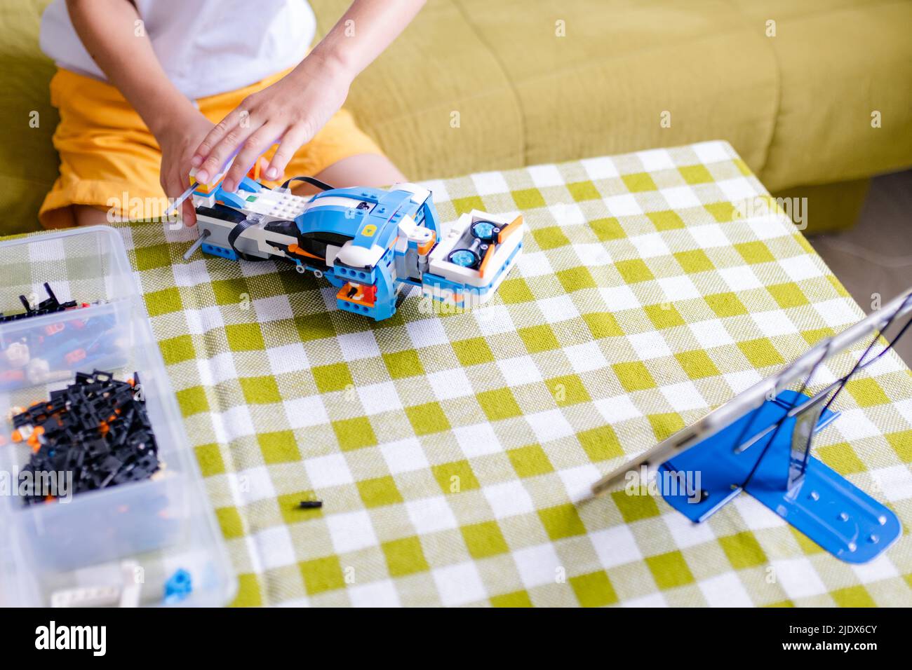 Kid collects robot from plastics details and programmed on tablet, robotics. Stock Photo