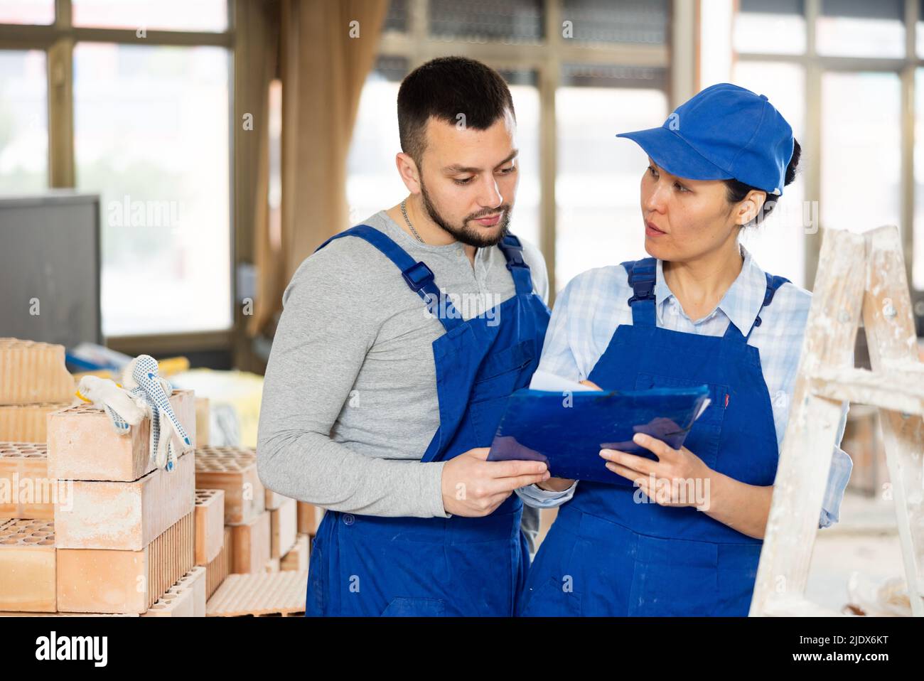Man and woman builders discussing project documentation Stock Photo
