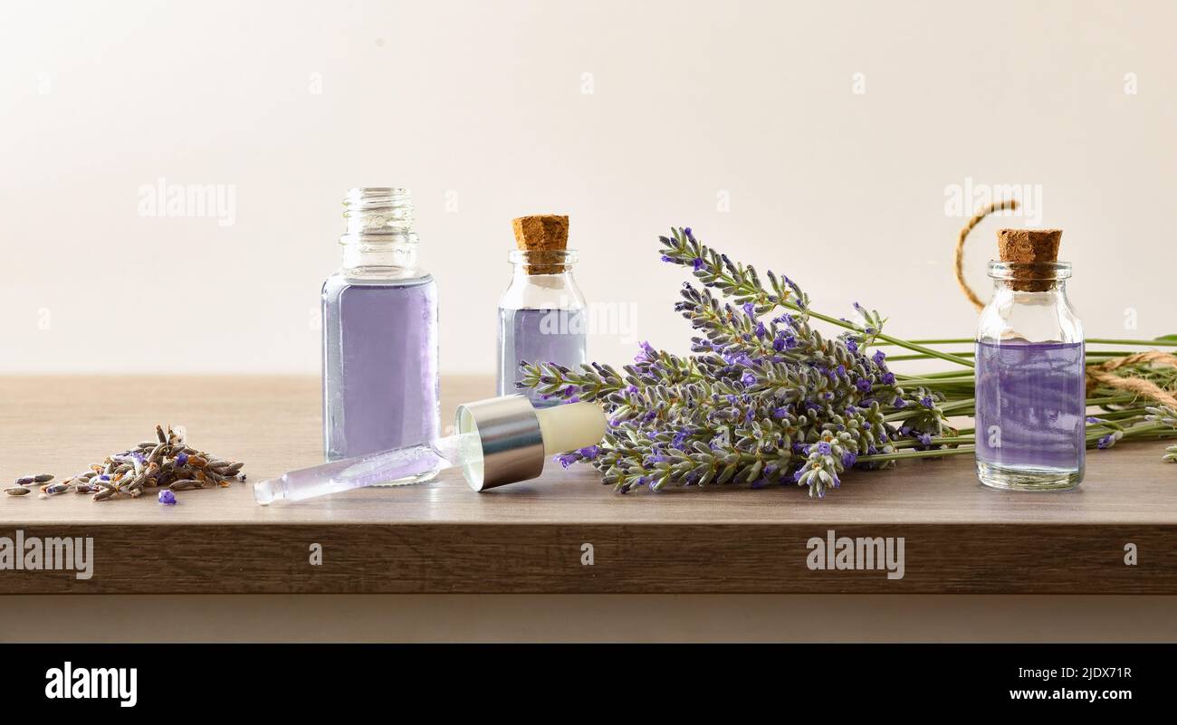 Medicinal lavender extract in glass bottles on wooden table with bunch of spikes and white isolated background. Front view. Horizontal composition. Stock Photo