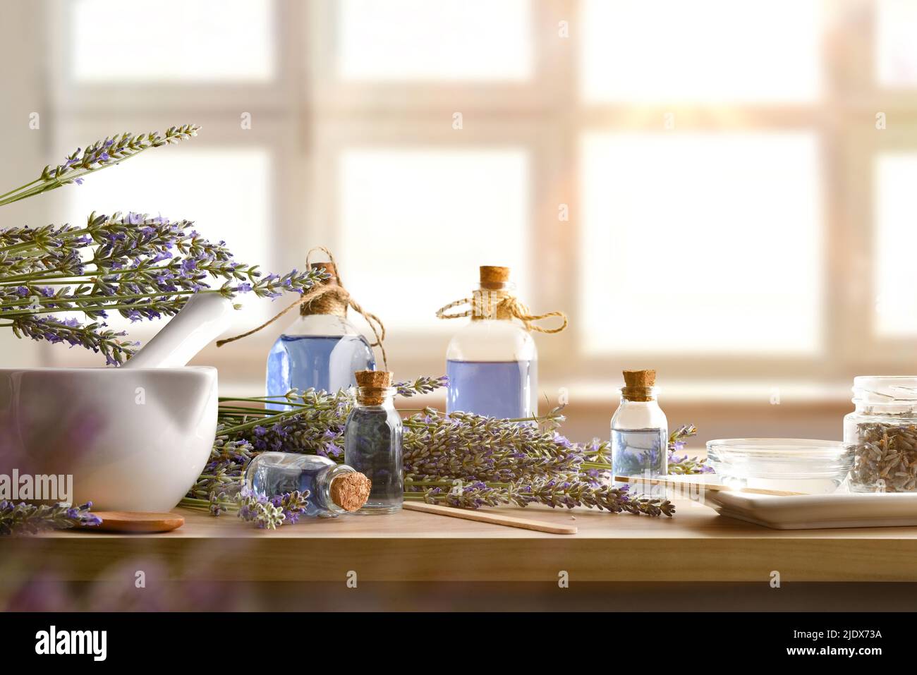 Natural essences freshly prepared at home on wooden table with spikes around and window background. Front view. Horizontal composition. Stock Photo