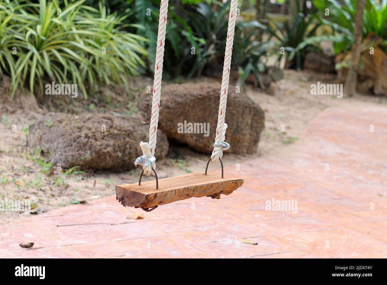 There is a wooden swing in the park for sitting. Stock Photo
