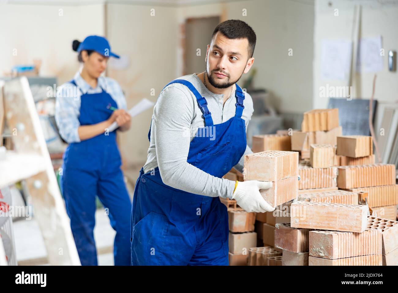 Builder carrying bricks while working in apartment Stock Photo