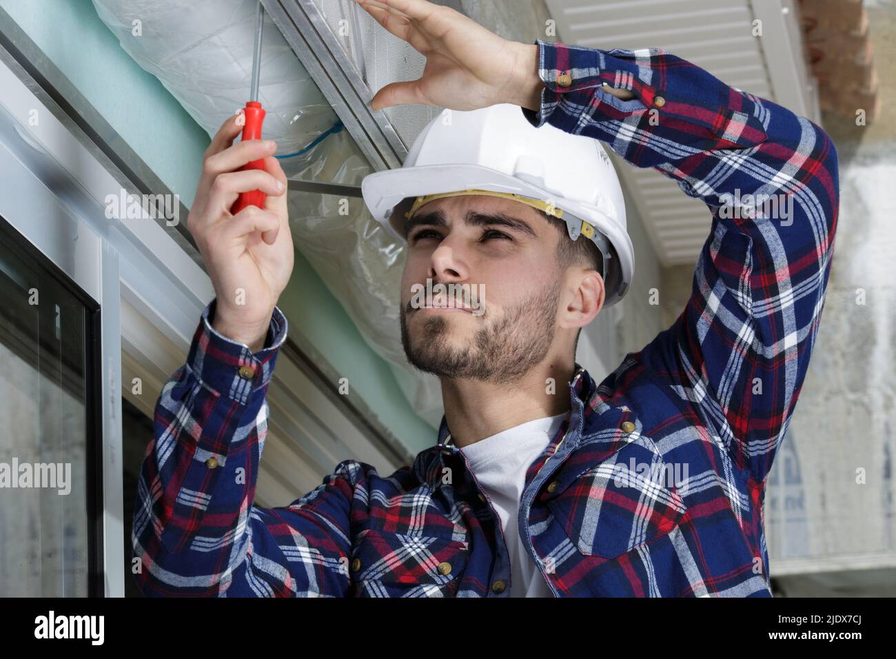 service man installing window with screwdriver Stock Photo
