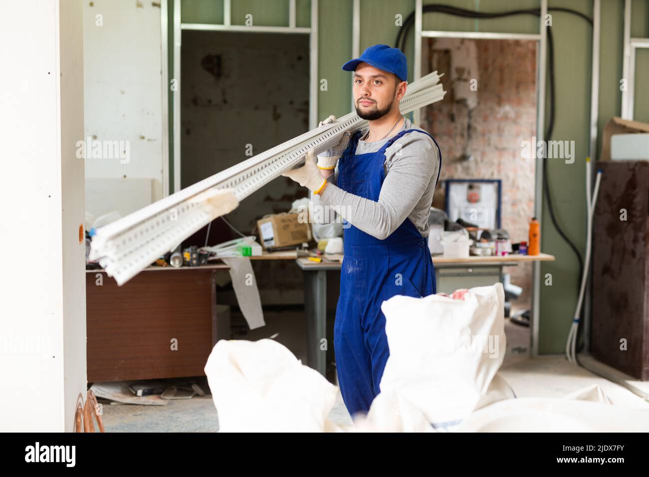 Overall Build Builder in blue overalls arranging metal square tubes while preparing ...