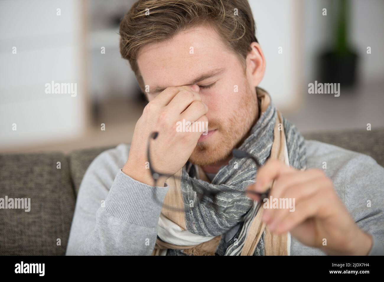 young man rubbing eye on white background annoying itch Stock Photo