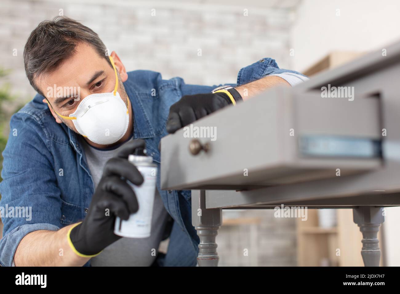 man painting desk at home with spray paint Stock Photo Alamy
