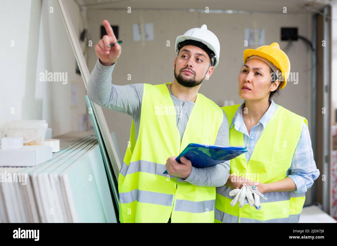 Two architects with papers discussing workflow at construction site Stock Photo