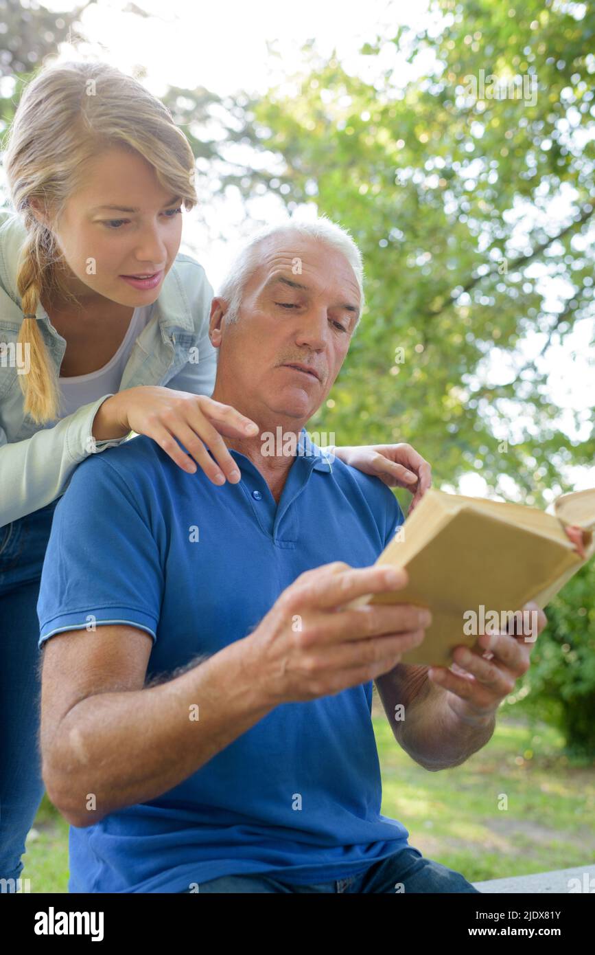 smiling worker reading book with older man Stock Photo