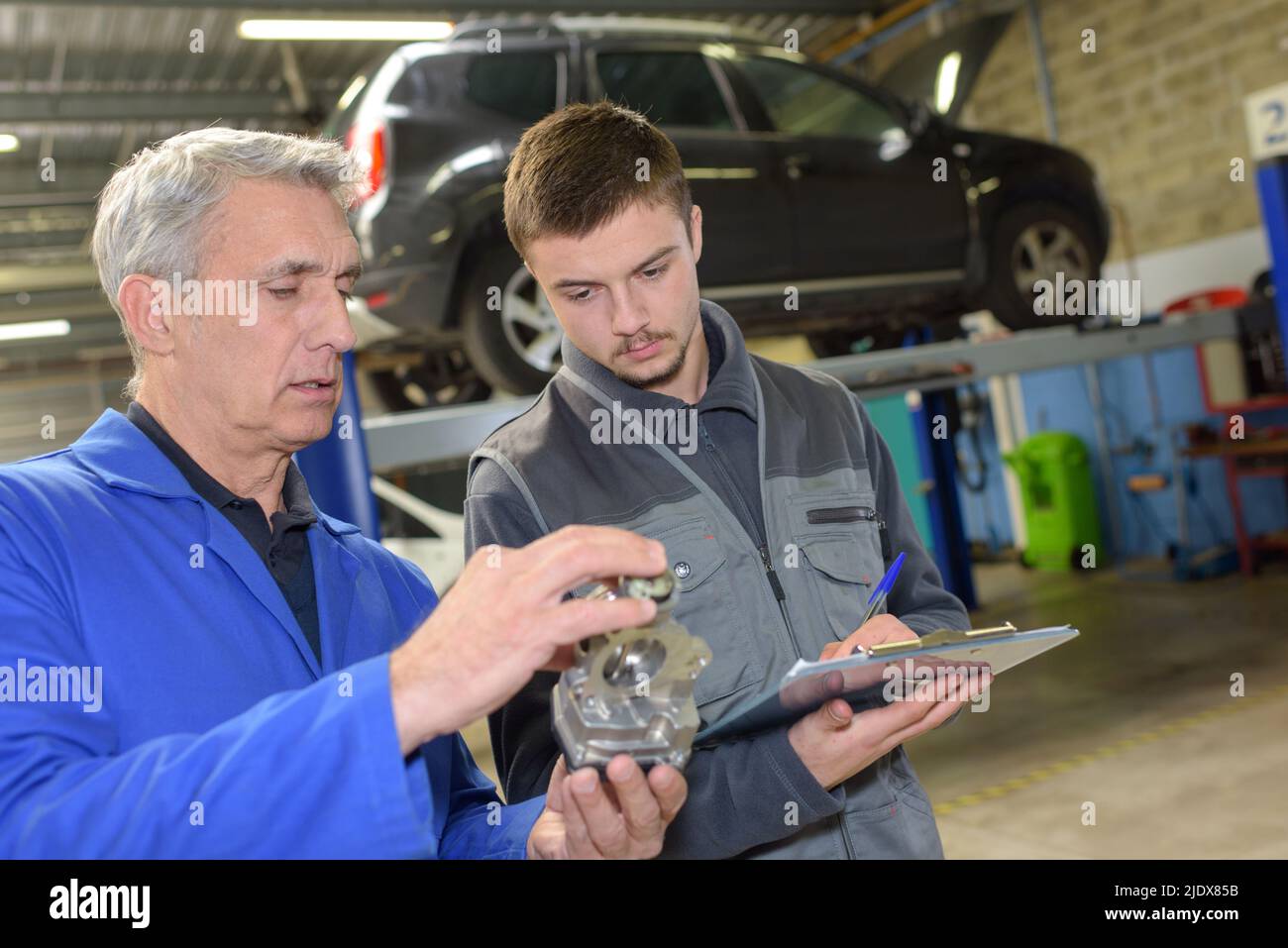 student with instructor repairing a car during apprenticeship Stock