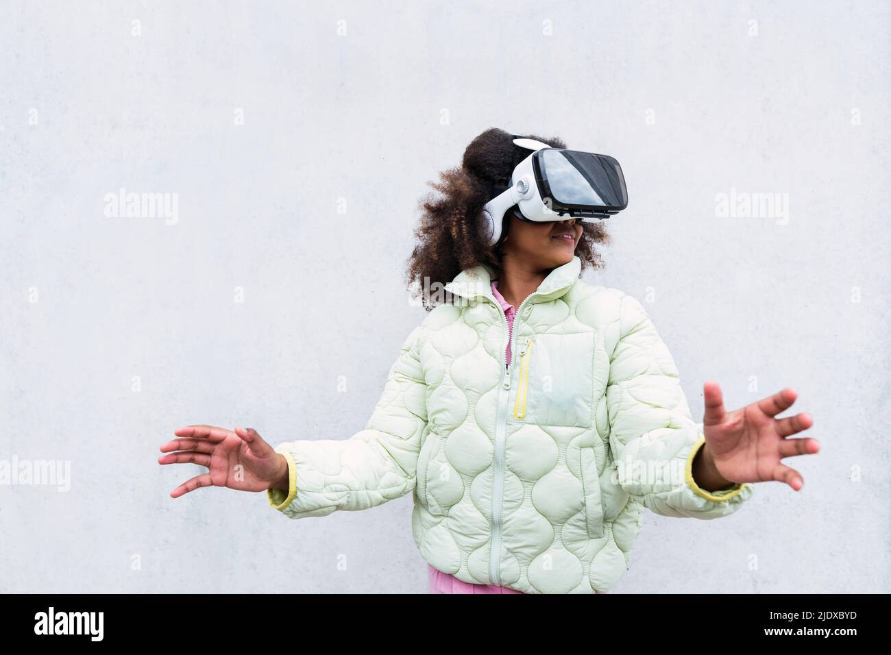 Girl wearing virtual reality headset gesturing in front of white wall ...