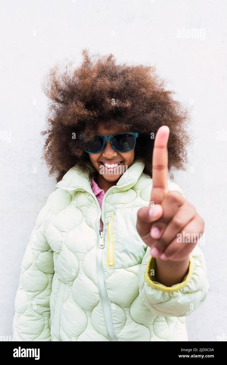 Smiling girl with sunglasses showing index finger Stock Photo