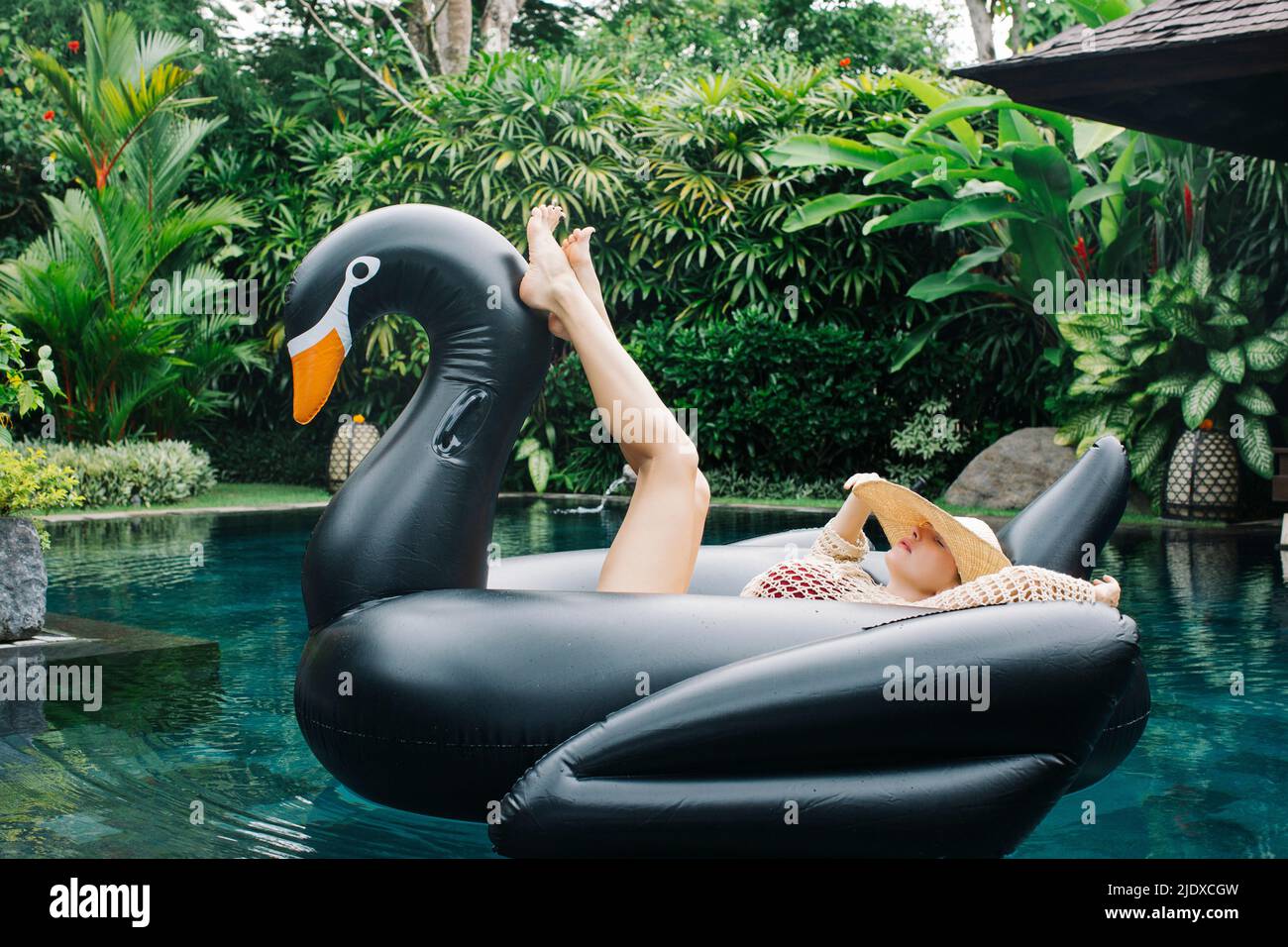 Young woman relaxing on swan shaped swimming float Stock Photo