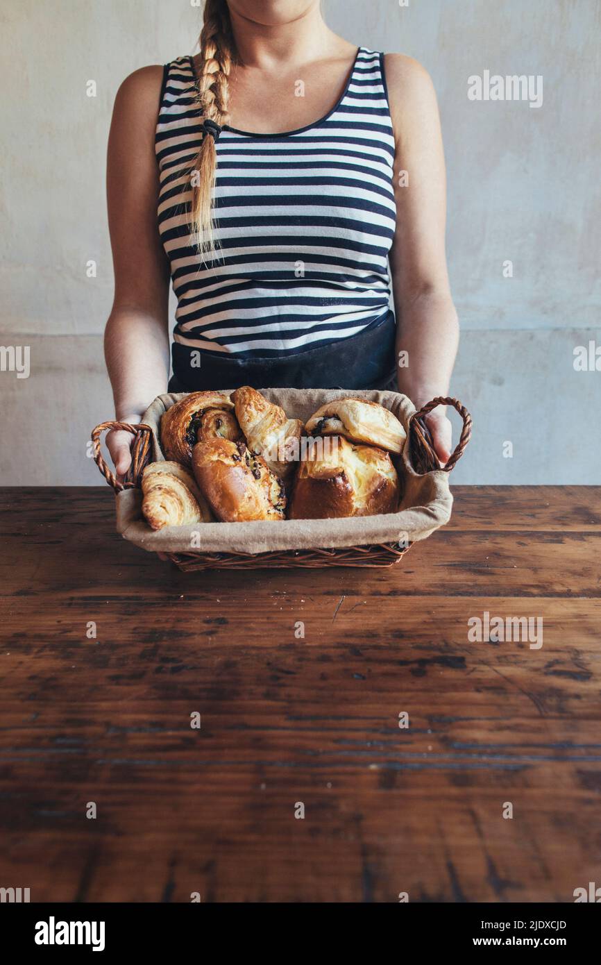 Bakery owner holding bread basket on table Stock Photo