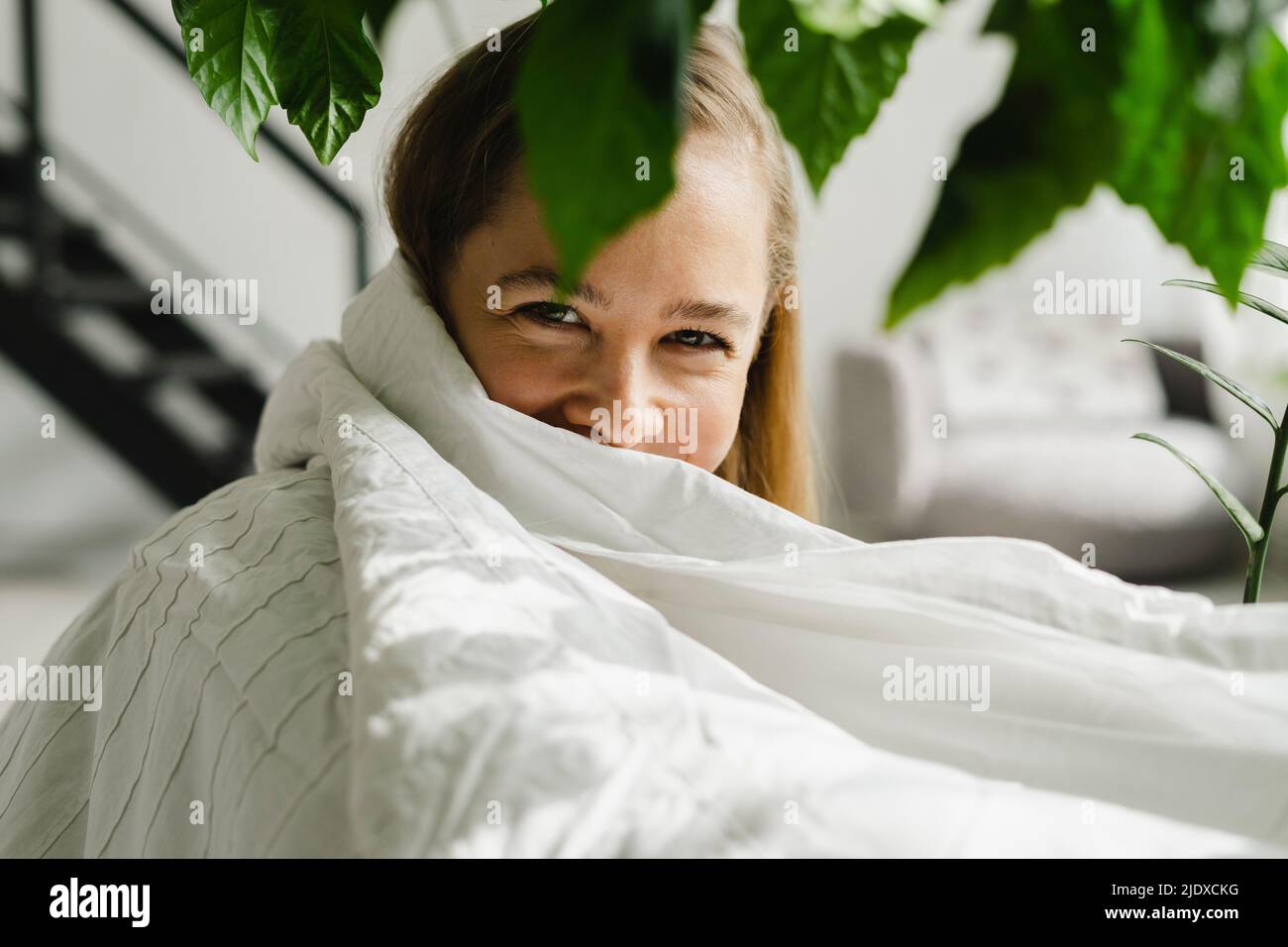 Woman wrapped in white blanket at home Stock Photo Alamy