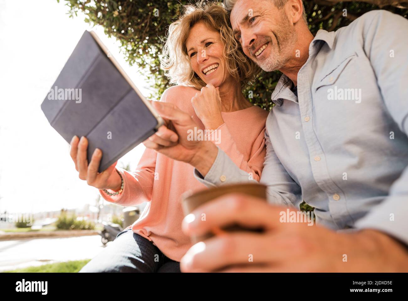 Happy mature couple using tablet computer in park Stock Photo