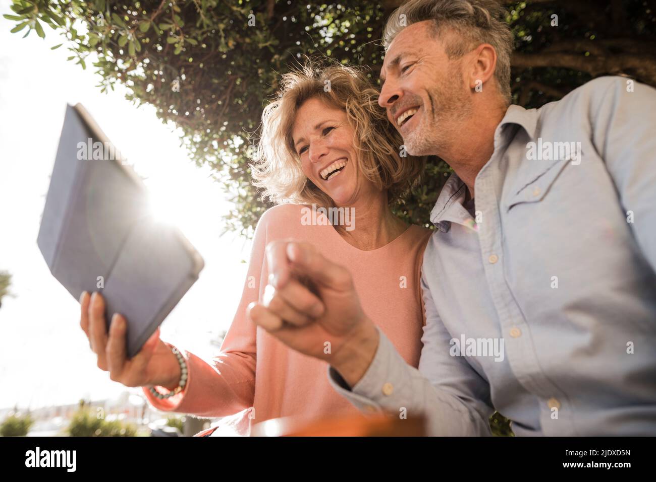 Cheerful mature couple using tablet PC in park Stock Photo
