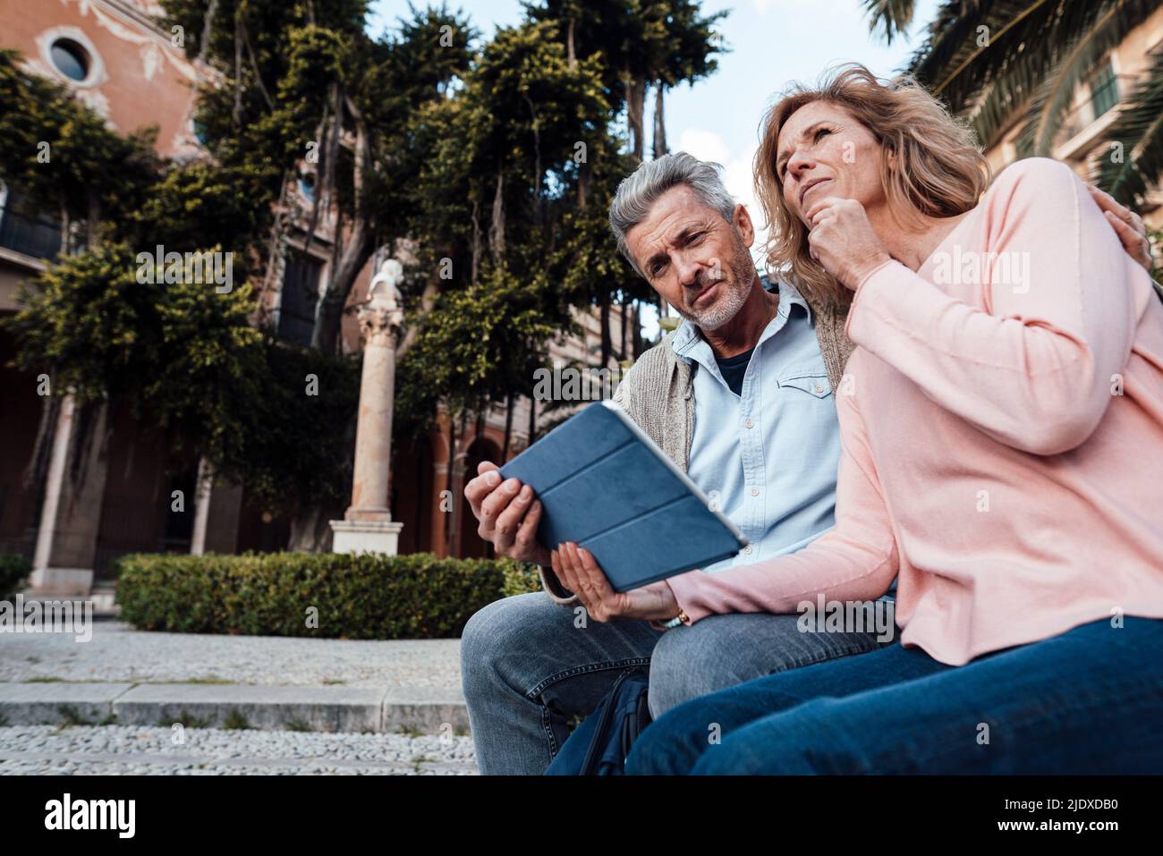 Mature man using tablet PC by thoughtful woman in park Stock Photo