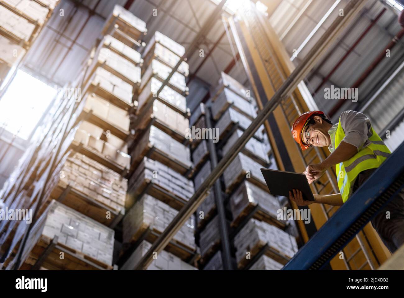 Happy worker wearing hardhat using tablet PC in warehouse Stock Photo
