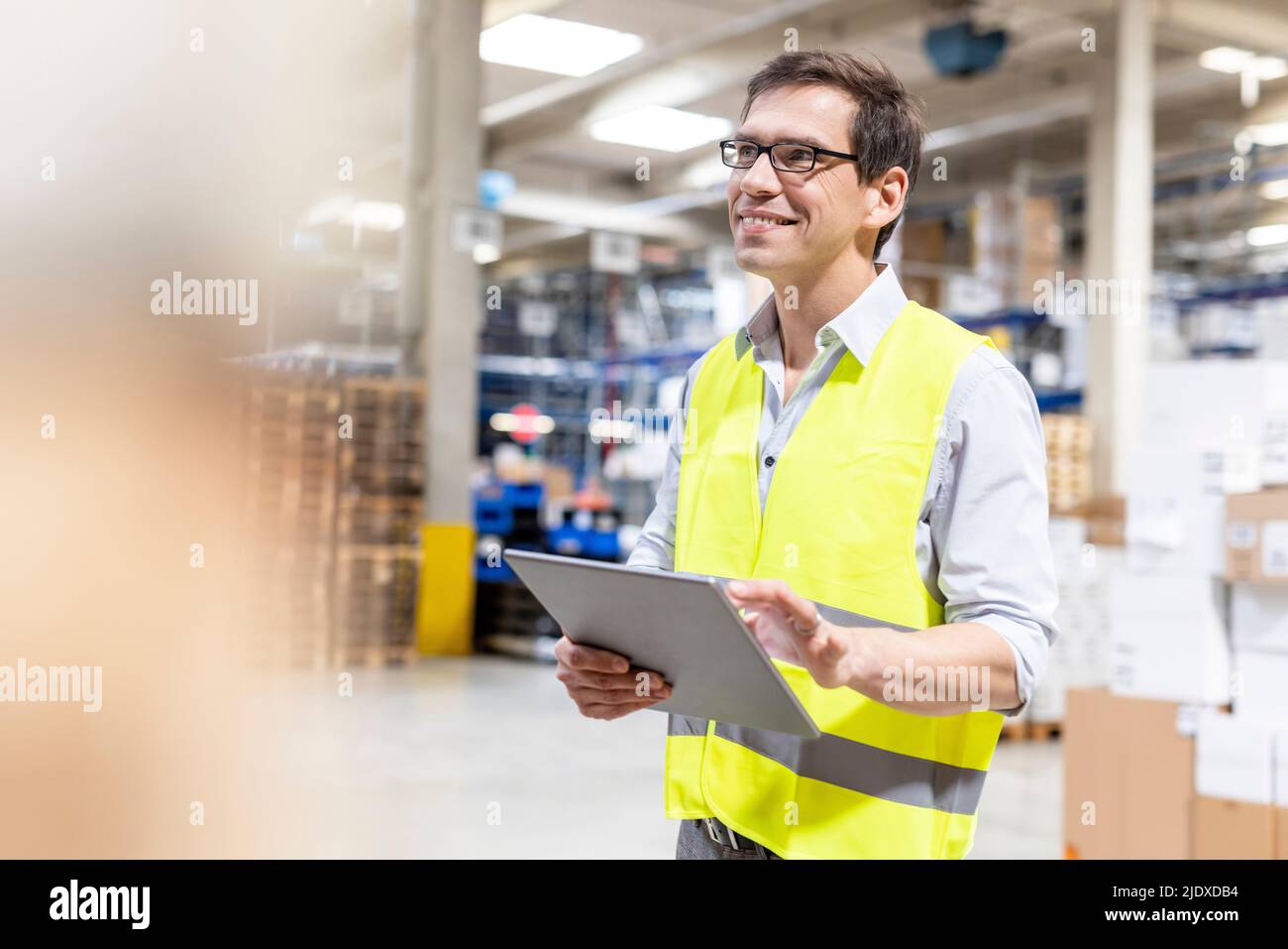 Smiling worker with tablet PC standing in warehouse Stock Photo