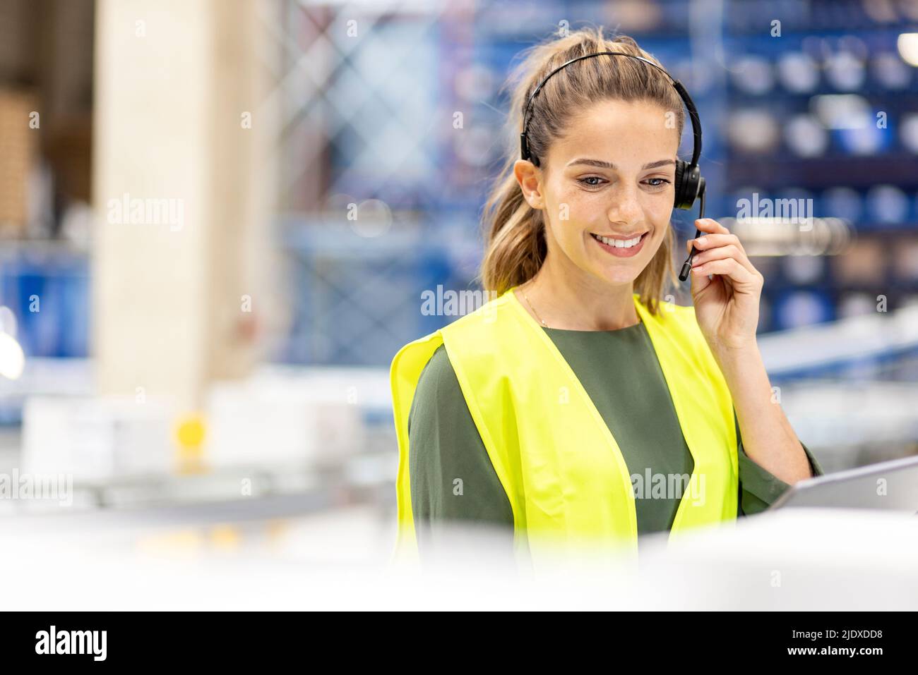 Happy worker talking through headset working in warehouse Stock Photo