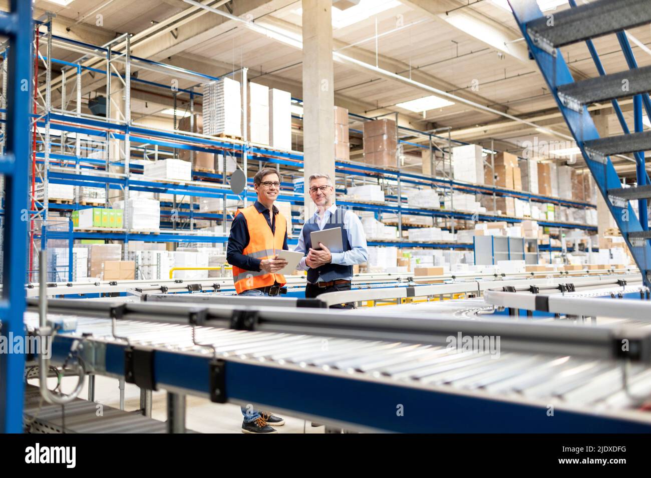 Smiling worker and manager standing with tablet PC in warehouse Stock Photo