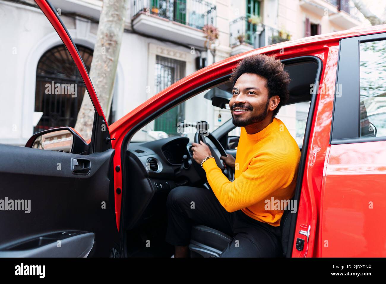 Smiling Afro man disembarking from car Stock Photo