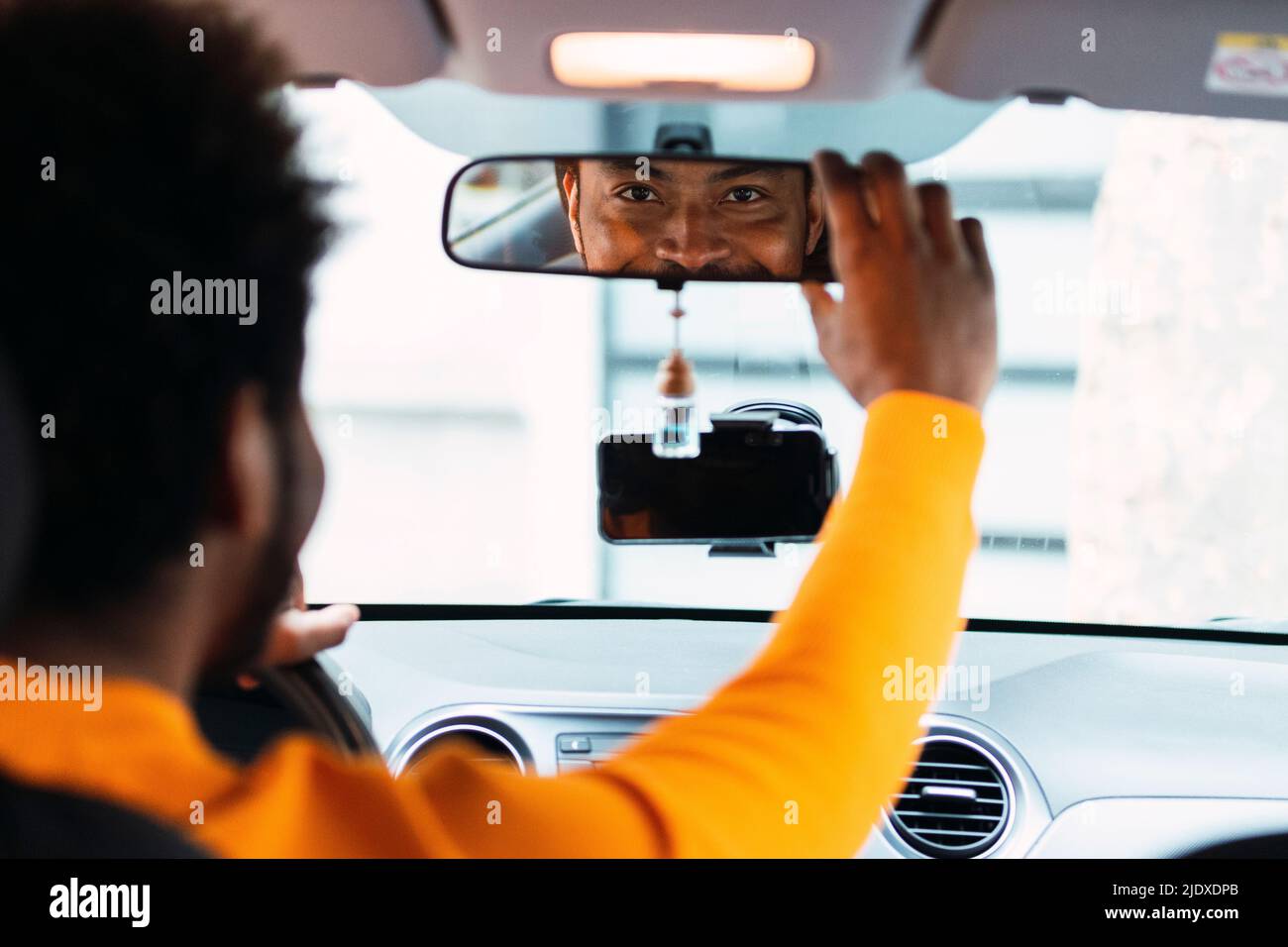 Smiling man looking in rearview mirror of car Stock Photo Alamy