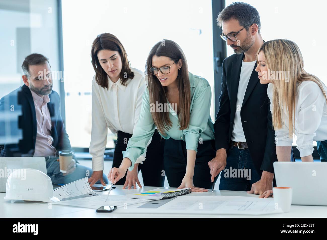 Businesswoman discussing plan over documents with colleagues at desk in office Stock Photo
