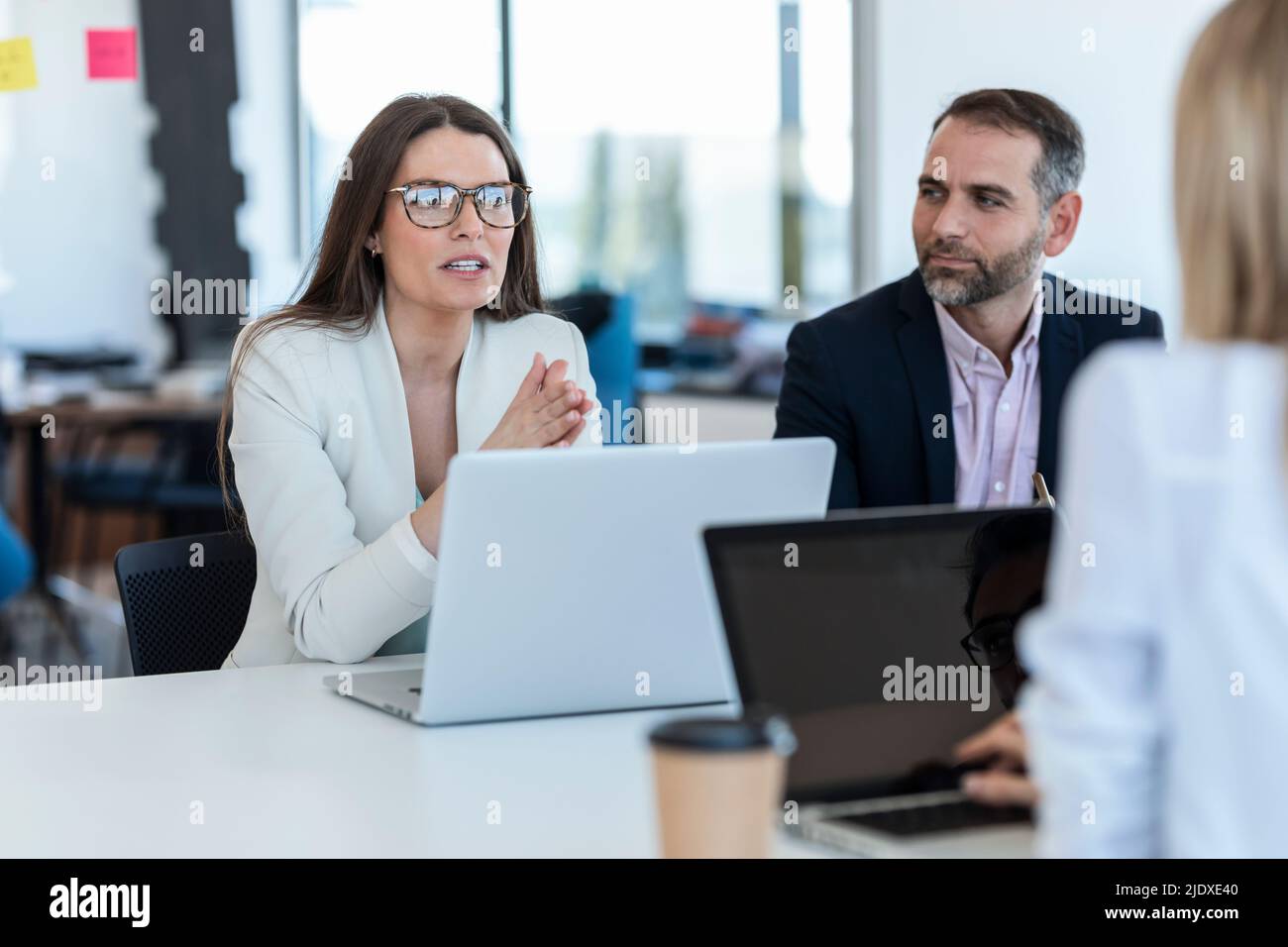 Businesswoman wearing eyeglasses discussing strategy with colleagues in