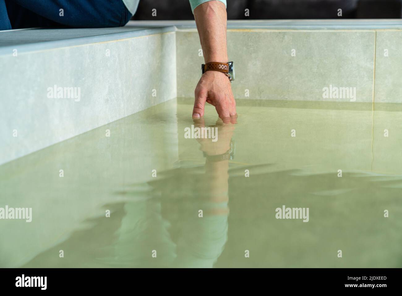 Man dipping hand in water at home Stock Photo