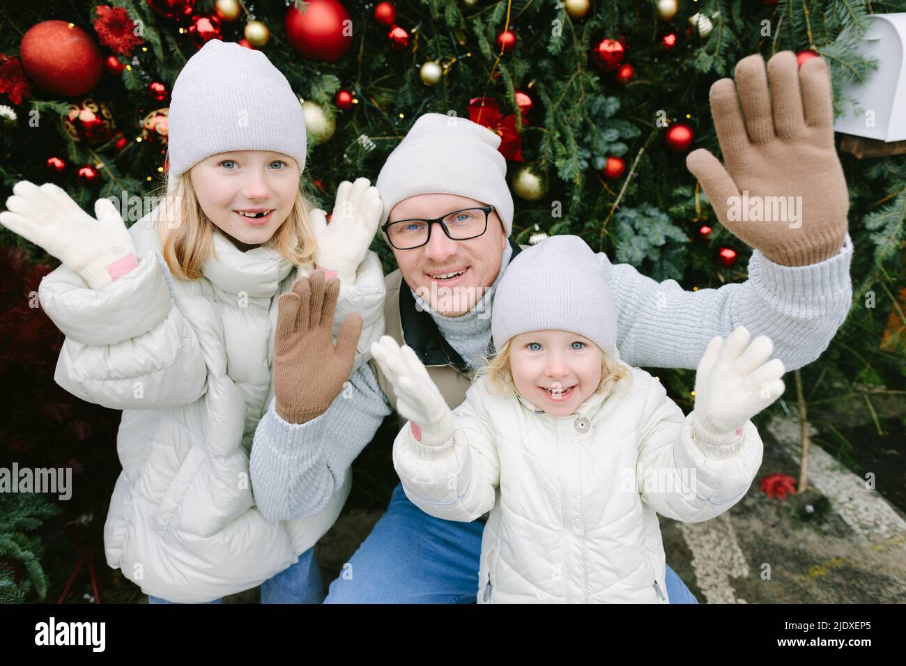 Smiling father with daughters gesturing in front of Christmas tree Stock Photo
