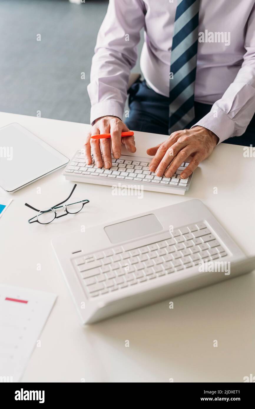 Hands of businessman typing on keyboard sitting at desk in office Stock Photo