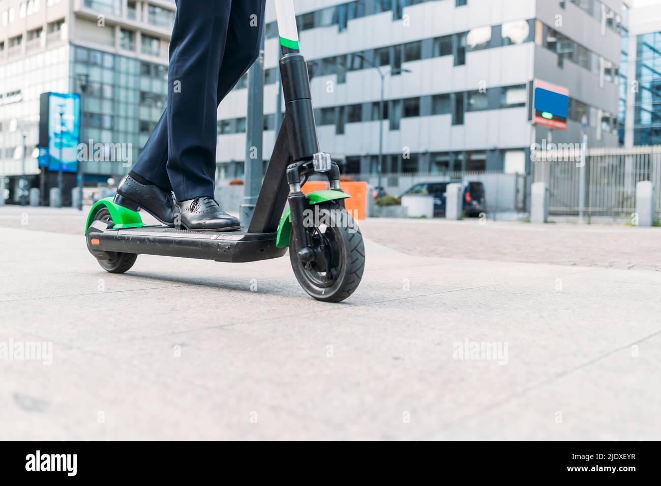 Businessman riding electric push scooter on footpath Stock Photo
