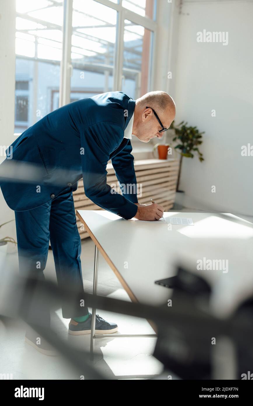 Businessman writing on document at desk Stock Photo