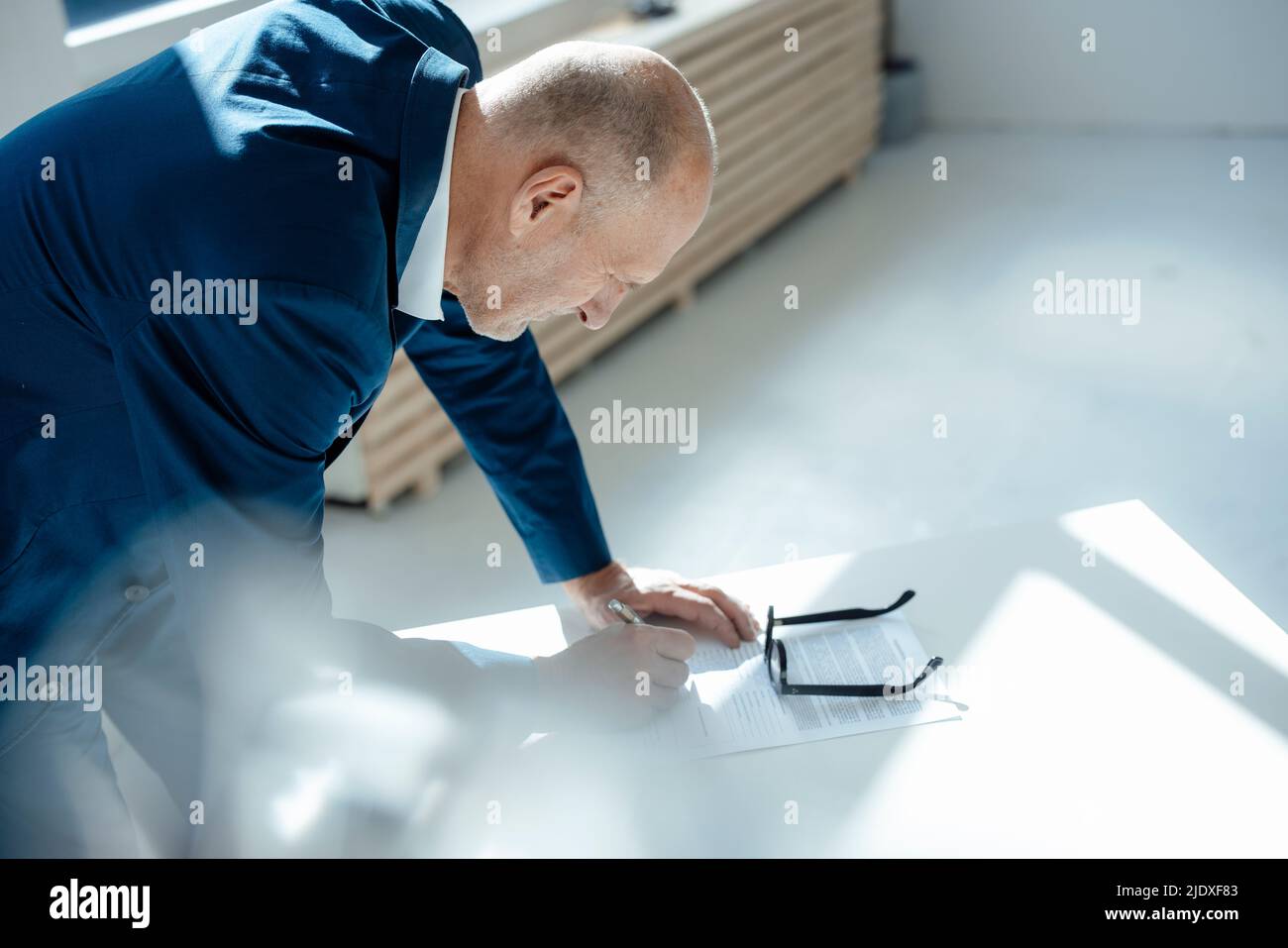 Senior businessman writing on document at desk Stock Photo