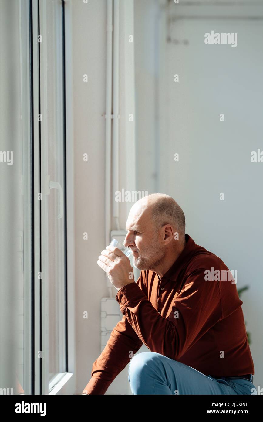 A person holding a glass of water in front of a window · Free Stock Photo