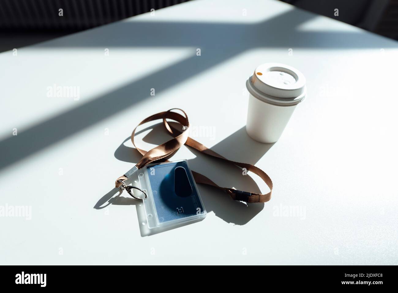 ID Card and disposable cup on white desk in office Stock Photo