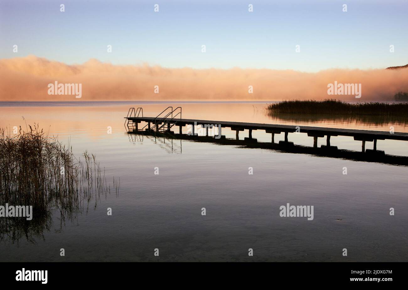 Austria, Upper Austria, Bathing jetty on shore of Mondsee lake with thick morning fog in background Stock Photo