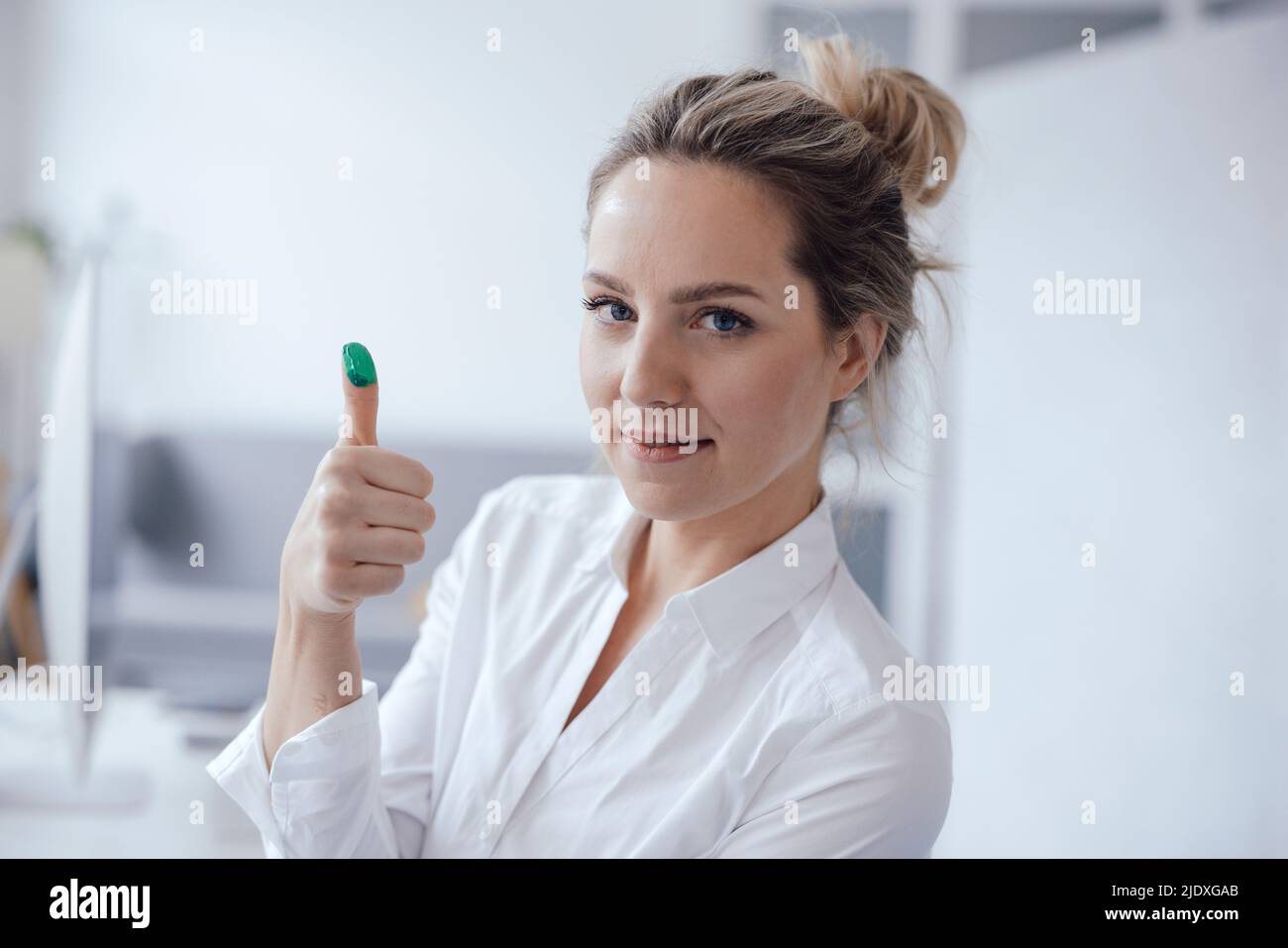 Businesswoman showing green color on thumb in office Stock Photo