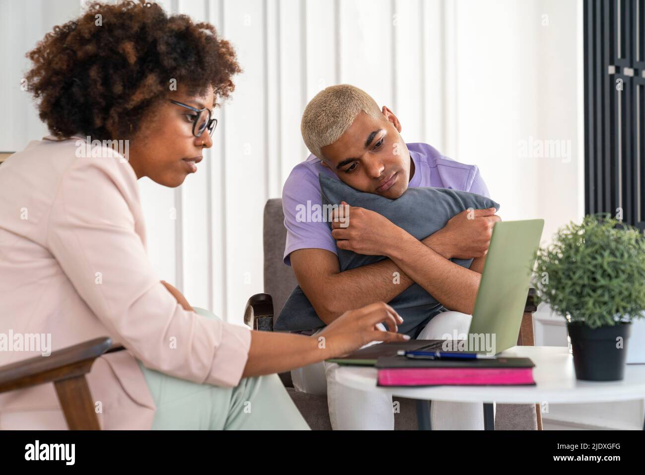 Young psychologist with patient discussing over laptop at office Stock Photo