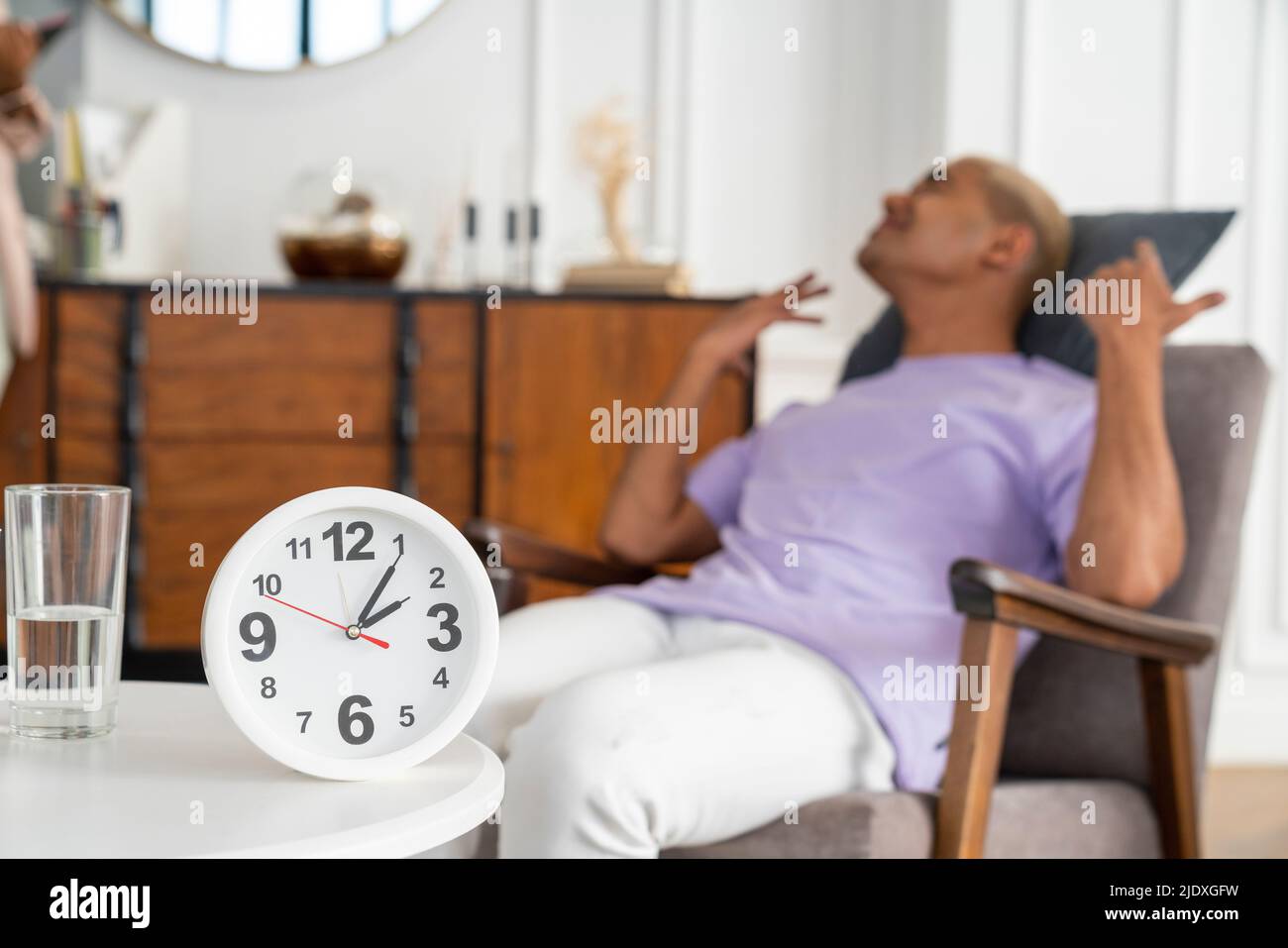 Clock on table with stressed patient sitting in armchair Stock Photo