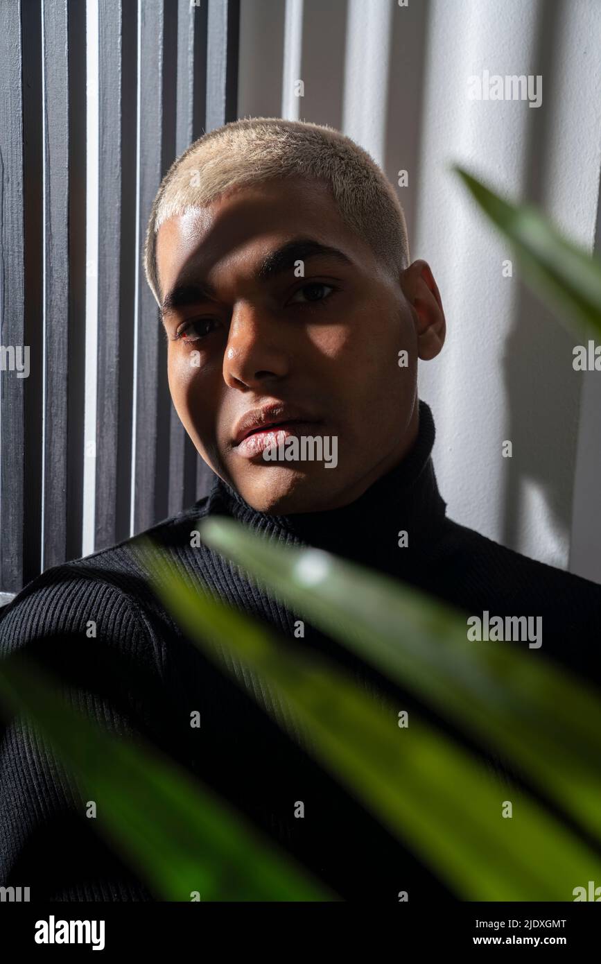 Young man with dyed blond short hair in front of wall Stock Photo