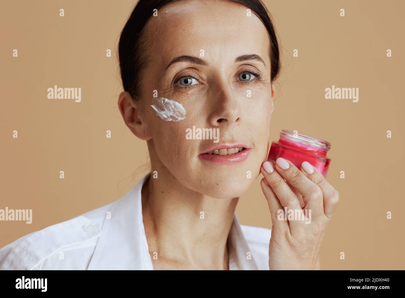 Modern Female With Facial Cream Jar In White Shirt Isolated On Beige