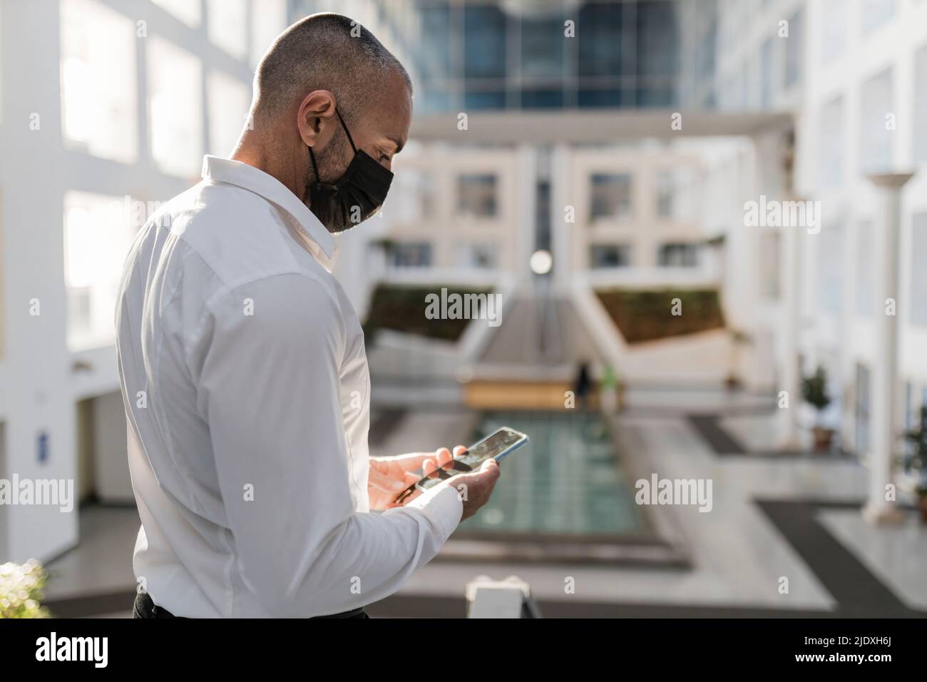 Man using smart phone wearing protective face mask Stock Photo