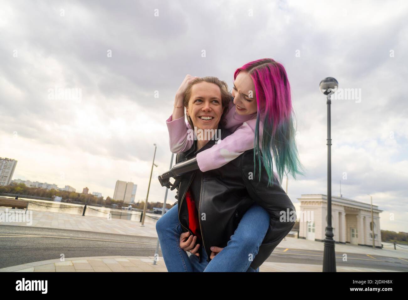 Happy young man giving piggyback ride to girlfriend with amputated hand Stock Photo