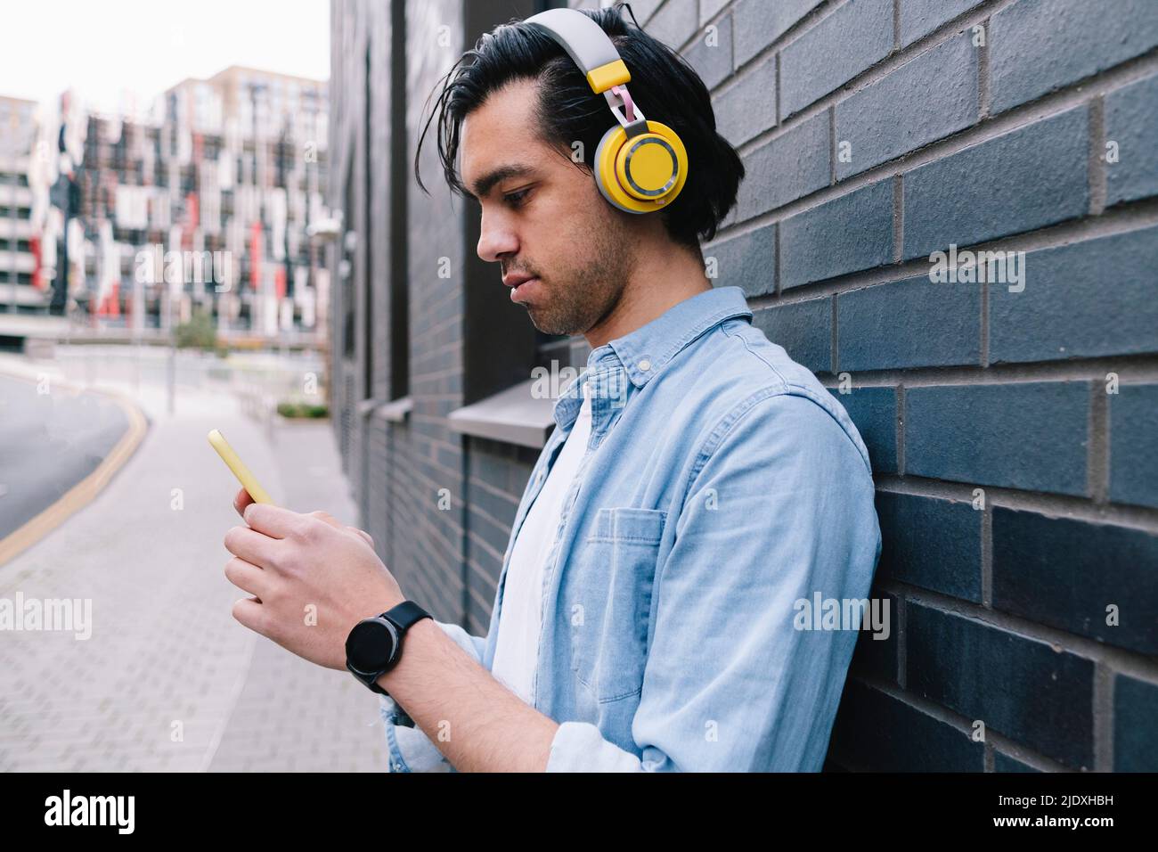 Man with headphones using smart phone near wall Stock Photo